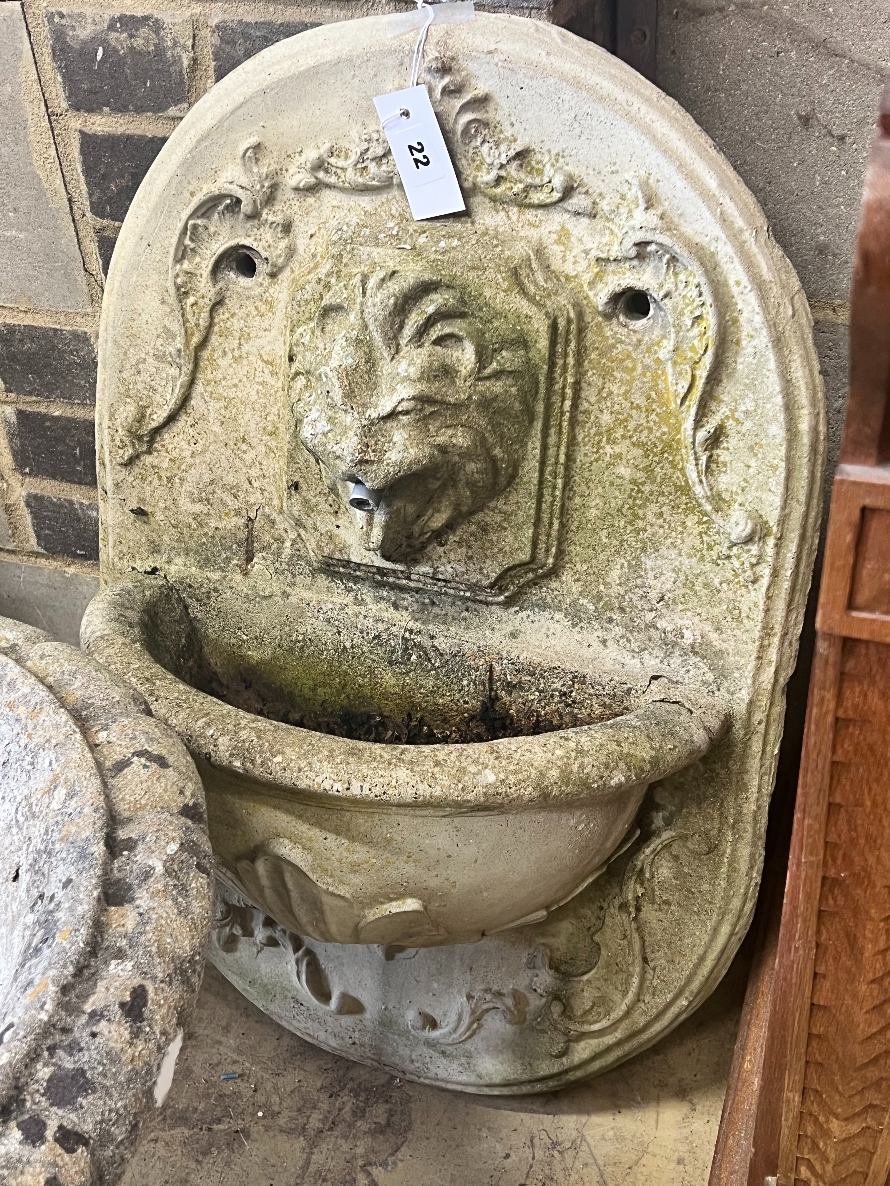A reconstituted stone garden wall mounted water fountain, with lion mask spout, width 48cm height 70cm